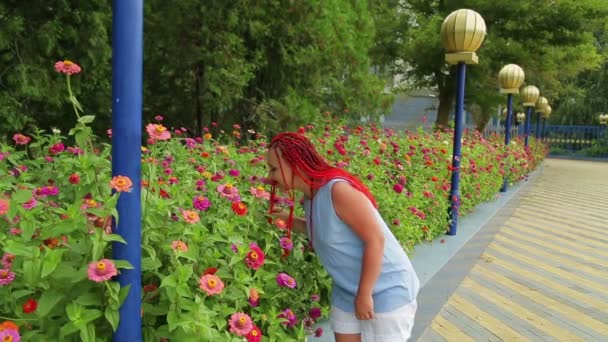 Kvinna med rött hår beundrar vackra blommor i parken — Stockvideo