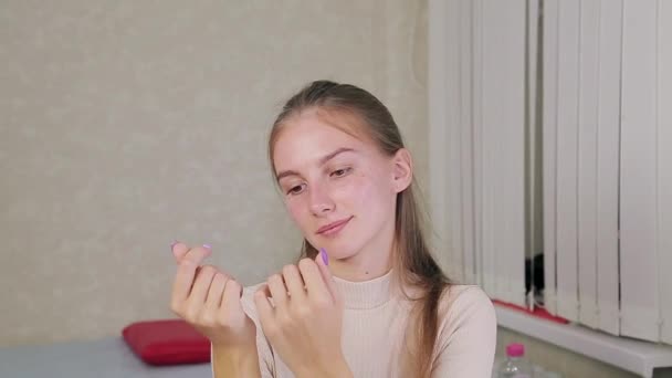 Una ragazza cliente di un salone di bellezza esamina il risultato finito di uno smalto gel manicure con un design — Video Stock
