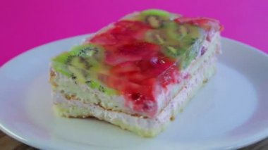 Meyveli kek jöleli beyaz bir tabakta döner..