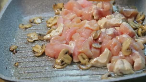 Il filetto di pollo sott'olio viene mescolato in una padella con una spatola di legno — Video Stock