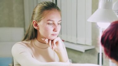 Jel cilası için oje hazırlama işlemi sırasında bir güzellik salonunun müşterisi. Yüzlerden ellere kaymaya odaklan