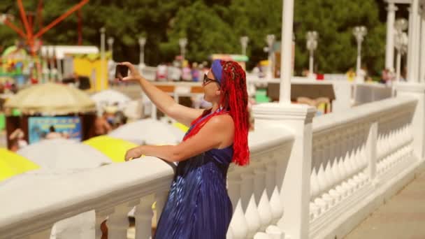 Radosna kobieta w niebieskiej sukience fotografuje morze z nabrzeża — Wideo stockowe