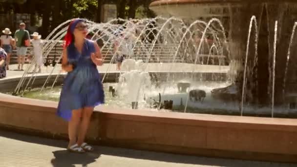 파란 드레스를 입고 공원의 샘에서 춤을 추는 명랑 한 여인. — 비디오
