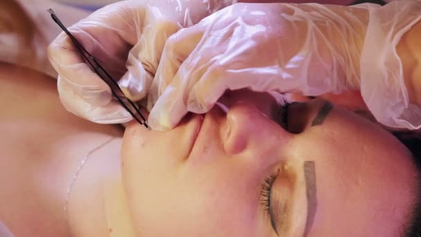 Die Kosmetikerin zupft sich die Haare vom Kinn und über der Oberlippe mit einer Pinzette — Stockvideo