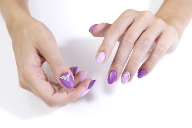 İki renkli ve yapay elmaslı manikür jeli cilalı bir müşterinin elleri.