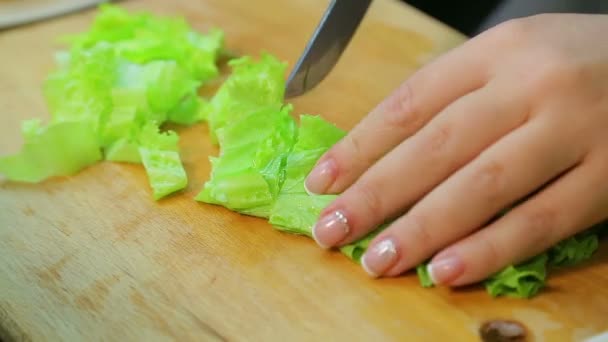 Női kéz késsel friss salátát vág egy fa deszkán. — Stock videók