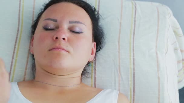 En manlig kosmetolog ger en kvinna en återfuktande ansiktsmask i en spasalong — Stockvideo