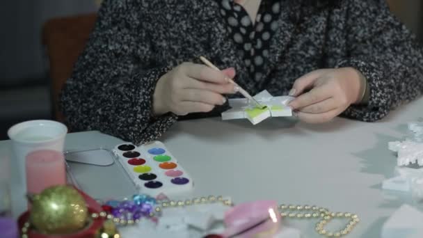 Egy fiatal nő lakberendezést készít karácsonyra csillagok festésével, akvarellekkel. — Stock videók