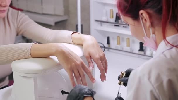 Vrouw manicure met handschoenen in een schoonheidssalon ontvet nagels van een klant voor het aanbrengen van de gel — Stockvideo