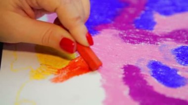 Kadın eli, gün batımında turuncu pastel bulutlu beyaz kağıda çizer.