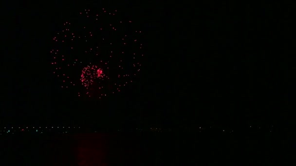 Φωτεινές σπινθήρες από εορταστικά πυροτεχνήματα στον νυχτερινό ουρανό πάνω από το ποτάμι που αντανακλάται στο νερό. Χρονογύροι — Αρχείο Βίντεο