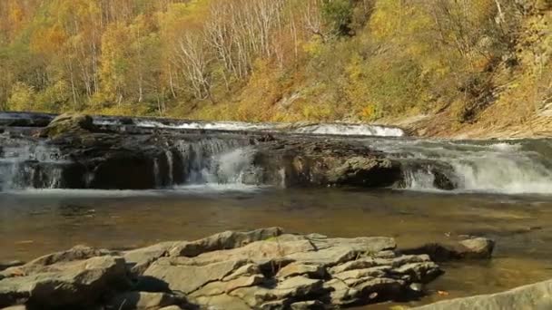 Cascadas bajas y un río de montaña con un arroyo sobre el telón de fondo de las montañas de otoño — Vídeo de stock