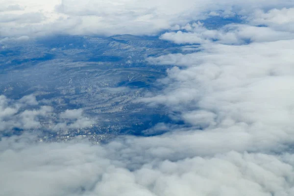 Bulutların üzerinde uçarken tepelerin zirvesinden bir manzara.