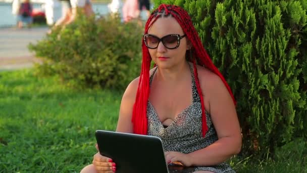 Mladá žena při západu slunce pracuje na dálku v zeleném parku — Stock video