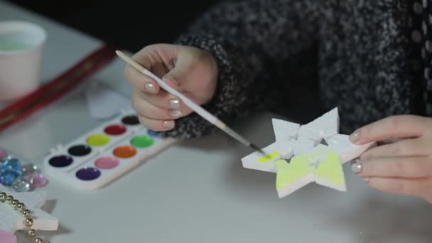 Молода жінка робить домашні прикраси на Різдво, малюючи зірки акварелями — стокове відео
