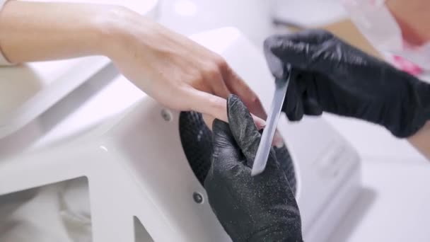 Seorang manikur dalam sarung tangan kuku klien dengan file kuku sebelum menerapkan lapisan gel — Stok Video