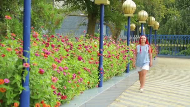 Vrouw met rood haar bewondert mooie bloemen in het park — Stockvideo