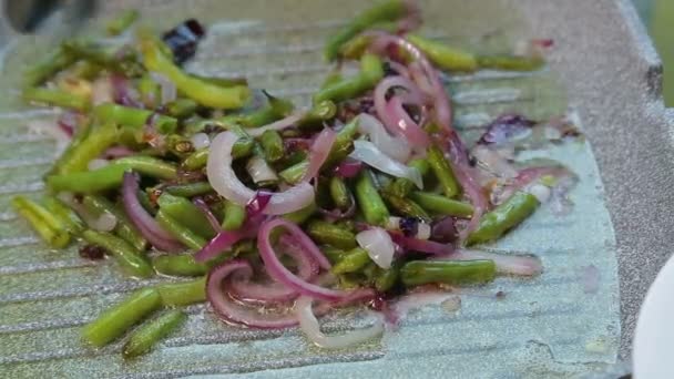 Female hand spreads fried green beans with onions in a white plate — Stock Video