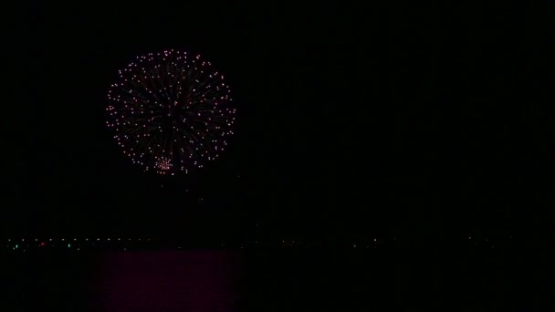 Brillos chispeantes de fuegos artificiales festivos en el cielo nocturno sobre el río que se refleja en el agua — Vídeos de Stock