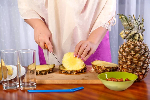 Kadın elleri tahta bir tahta üzerinde bir bıçak ile bir ananas kesti.