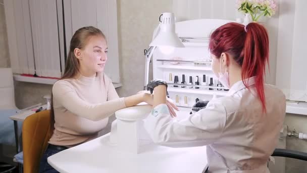 Vrouw manicure in handschoenen in een schoonheidssalon veegt een klant nagels met een natte handdoek — Stockvideo