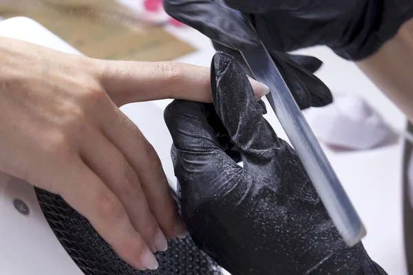 Un manicurista lucida le unghie di un cliente preparandosi per il rivestimento grossolano del gel delle loro mani . — Foto Stock