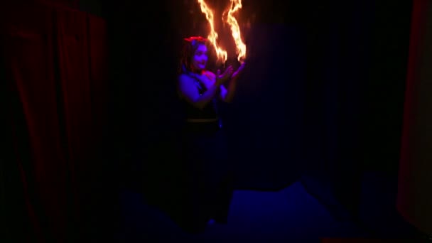 Mujer diablo bailando con corrientes de fuego en sus manos sobre un fondo negro . — Vídeos de Stock