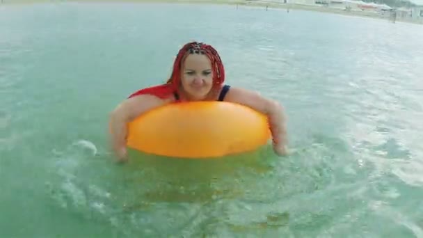 En ung kvinna simmar i havet i en badcirkel. — Stockvideo