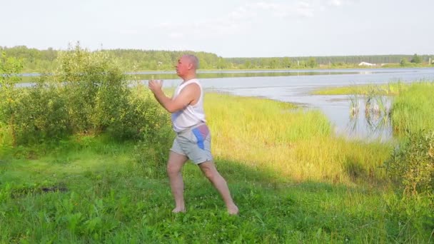 En medelålders man andas yoga på sjön på morgonen — Stockvideo