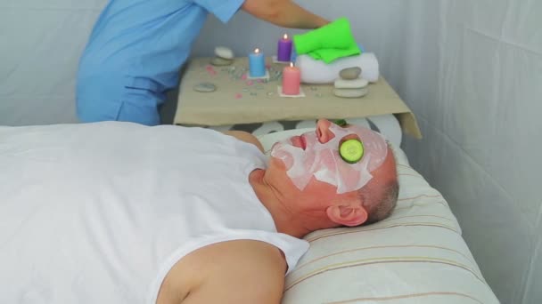 Een vrouwelijke schoonheidsspecialiste maakt plantaardige therapie op het gezicht van een man. — Stockvideo
