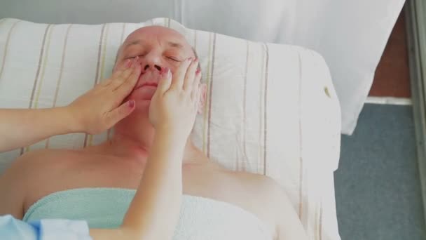 Mulher esteticista dá ao homem uma massagem facial firme em um salão de spa — Vídeo de Stock