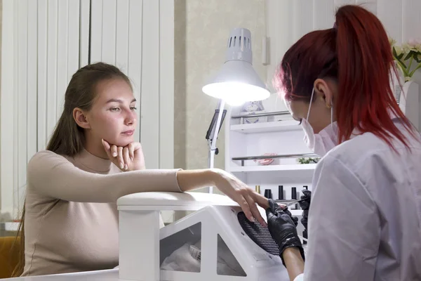 Een manicure in een schoonheidssalon poetst nagels van een klant voor te bereiden op gel coating. — Stockfoto
