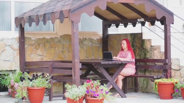 Mujer joven freelancer trabajando con un ordenador portátil de vacaciones en la terraza — Vídeo de stock