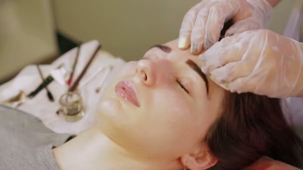 Косметолог моет хну с бровей клиента и наносит специальный крем — стоковое видео