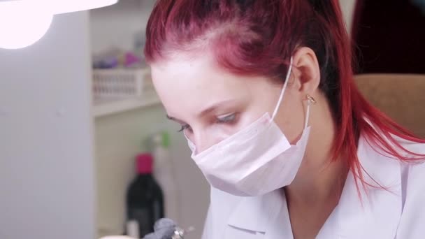 Vrouw manicure met handschoenen in een schoonheidssalon doet een hardware manicure aan een klant voor het aanbrengen van een gel coating — Stockvideo