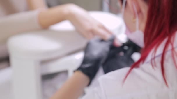 Vrouw manicure met handschoenen in een schoonheidssalon doet een hardware manicure aan een klant voor het aanbrengen van een gel coating. vertaling van vervaging naar scherper — Stockvideo