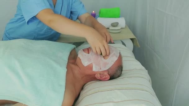 Un'estetista femminile rimuove una maschera idratante dal viso di un uomo — Video Stock