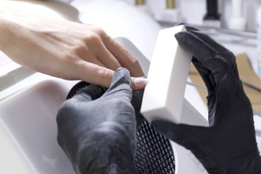 Manikürcü elleri muayene eder ve müşterilerin tırnaklarını cilalar..