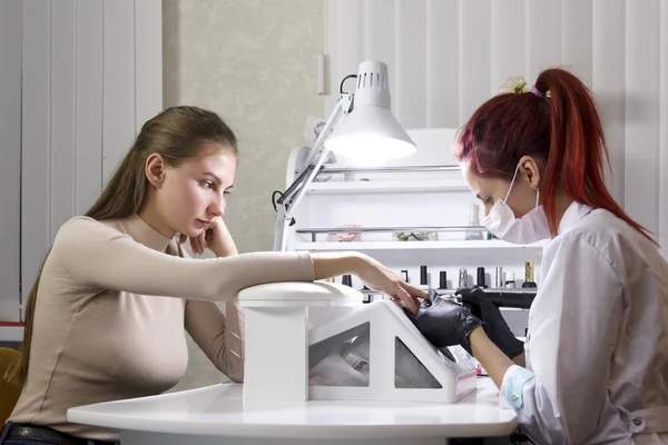 Een manicure in een schoonheidssalon maakt van een klant een hardware manicure. — Stockfoto