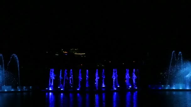 Un espectáculo multicolor de fuentes sobre el fondo del cielo nocturno reflejado en el agua. — Vídeos de Stock