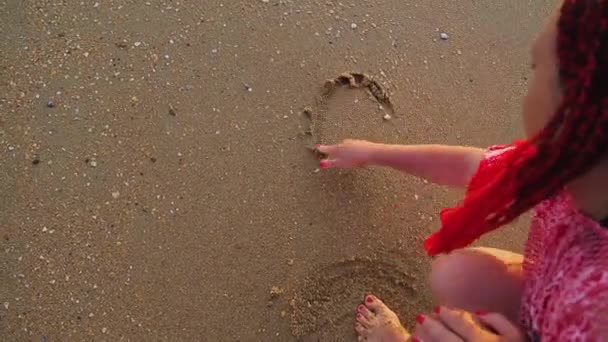 Eine Frau schreibt in den Sand, dass das Wort Co-Welle weggespült wird. — Stockvideo