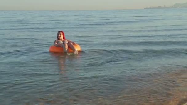 Mayo giyen bir kadın, yüzme çemberinde deniz dalgalarında salyalar — Stok video