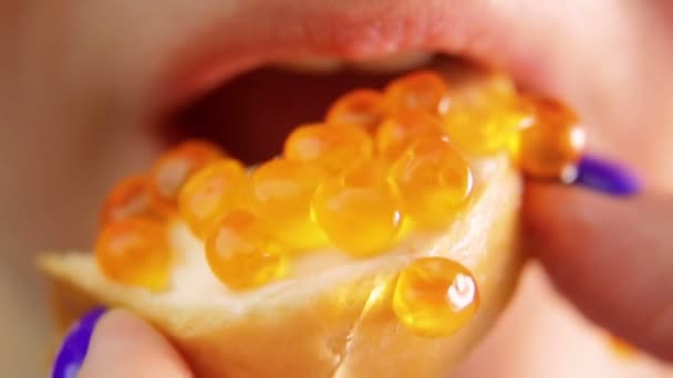 Female mouth bites from a sandwich with caviar and chews. — Stockvideo