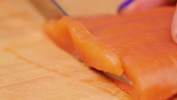 Female hand cuts trout fish for sandwiches on a wooden board — Stockvideo