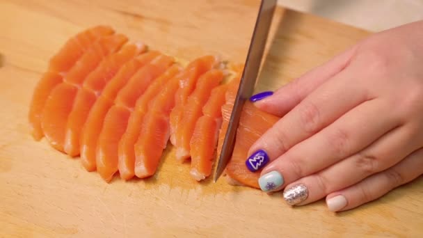 Weibliche Hand schneidet rote Forellen für Sandwiches auf einem Holzbrett. — Stockvideo