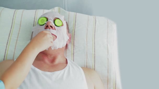 A female beautician removes a moisturizing face mask from a client in a spa salon — Stock Video