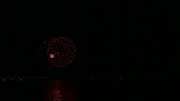 Fuegos artificiales de colores festivos en el cielo nocturno sobre el río con reflejo en el agua — Vídeos de Stock