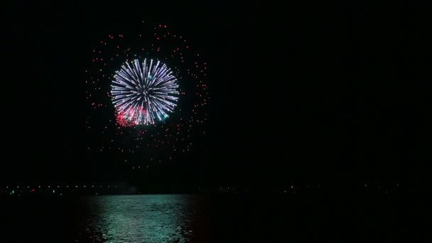 Brilhantes faíscas de fogos de artifício festivos no céu noturno acima do rio refletindo na água — Vídeo de Stock