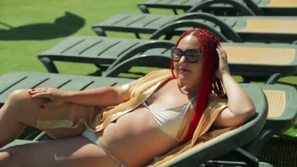 Єврей у відпустці сонячні ванни на шезлонгу біля басейну — стокове відео
