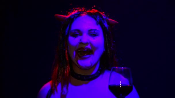 Γυναίκα διάβολος με ένα δυσοίωνο χαμόγελο στο πρόσωπό της πίνει αίμα από ένα ποτήρι σαν πρόσωπο κρασιού στο αίμα — Αρχείο Βίντεο